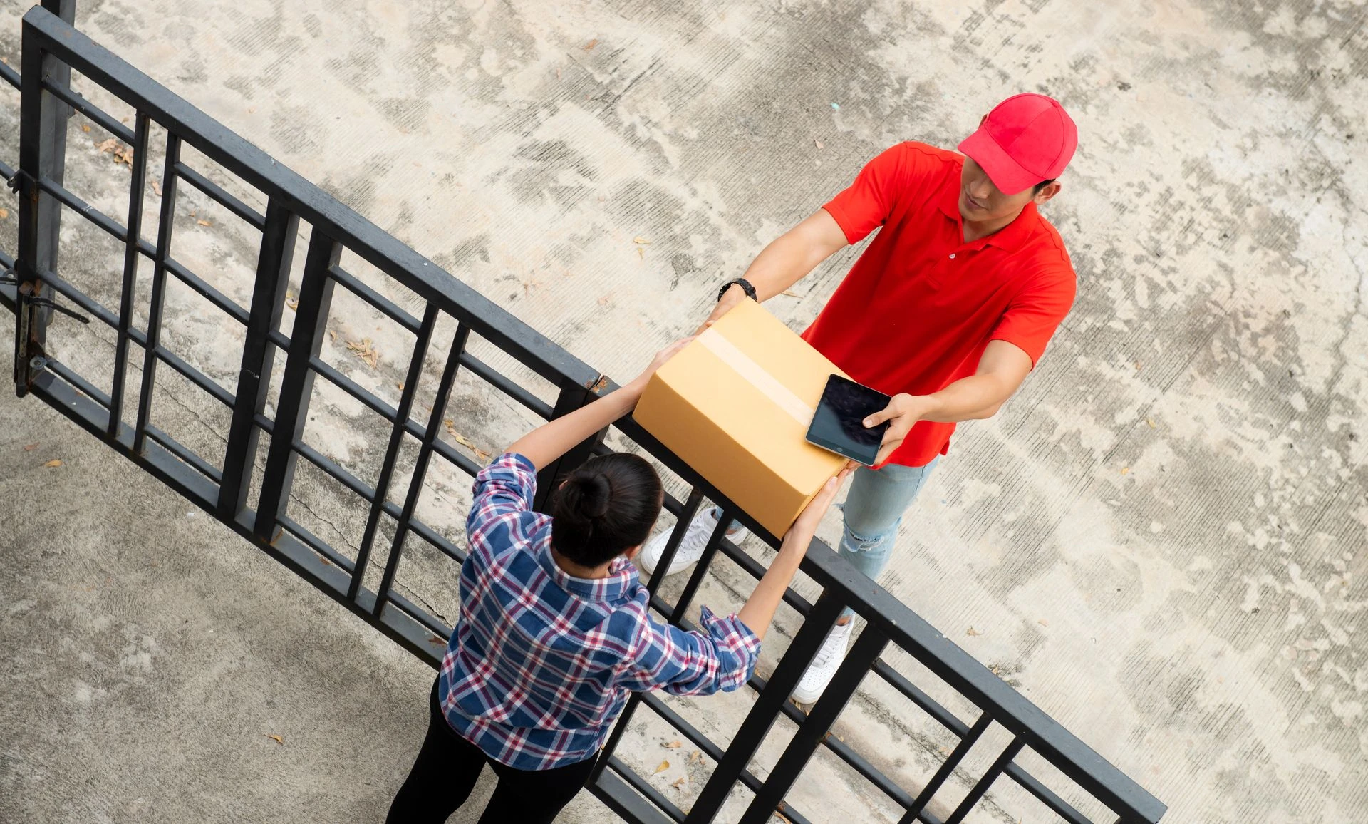 Delivery man using tablet computer appending signature after receiving parcel from courier on fence,Hand man sending a box to customer as a sign receive a parcel,Asian man receiving a package at home.